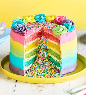 Slica of multicolored rainbow cake in white plate on grass. Cake with  layers of bright colors inside Stock Photo - Alamy