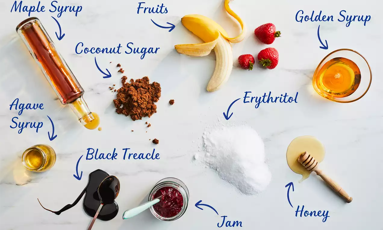 Assortment of sugar alternatives on a white marble surface with fruits, powders, syrups in jars and spoons arranged neatly